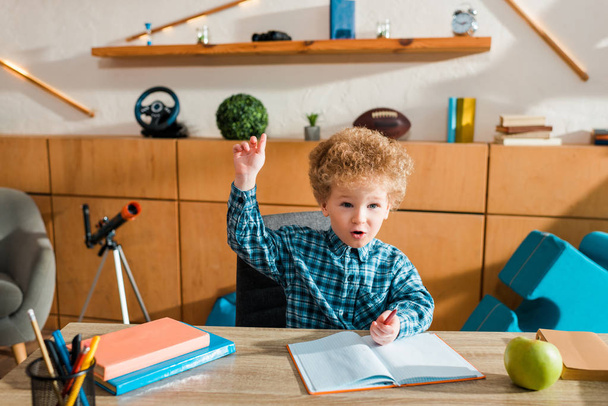 cute and smart kid with raised hand at home - Photo, Image