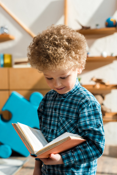 smiling and smart child reading book at home - Foto, Imagen
