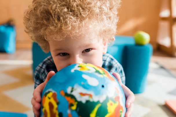 selective focus of smart kid holding globe and looking at camera - Photo, Image