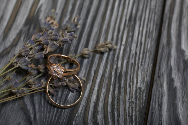Wedding rings lie next to a bouquet of lavender. On brushed pine boards painted in black and white. - Fotó, kép