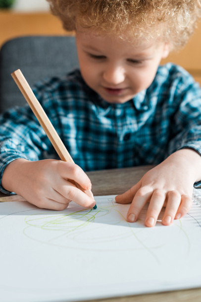 Kıvırcık çocuğun kağıda çiziminin seçici odağı  - Fotoğraf, Görsel