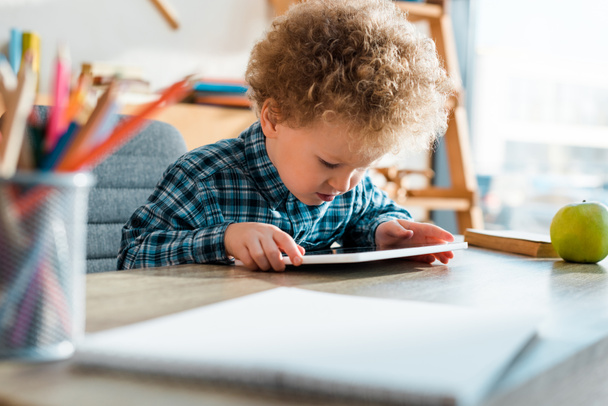 foyer sélectif de l'adorable et frisé enfant en utilisant une tablette numérique
  - Photo, image