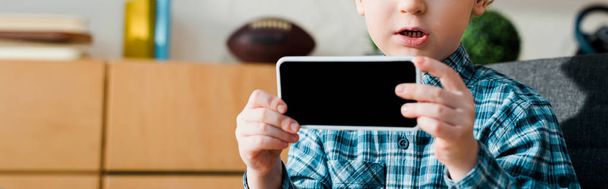 panoramic shot of cute boy holding smartphone with blank screen  - Photo, Image