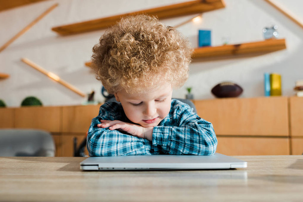 στοχαστικό παιδί που κοιτάζει το φορητό υπολογιστή στο σπίτι - Φωτογραφία, εικόνα