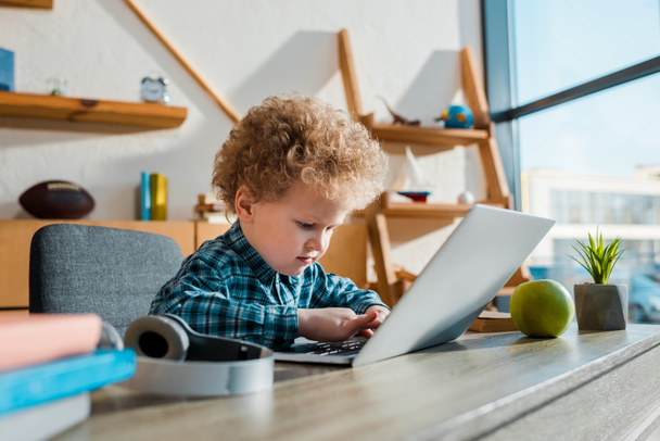 szelektív fókusz a gyerek gépelés laptop közelében vezeték nélküli fejhallgató  - Fotó, kép