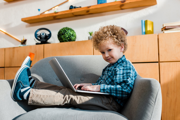 criança feliz sentado em poltrona e usando laptop
  - Foto, Imagem