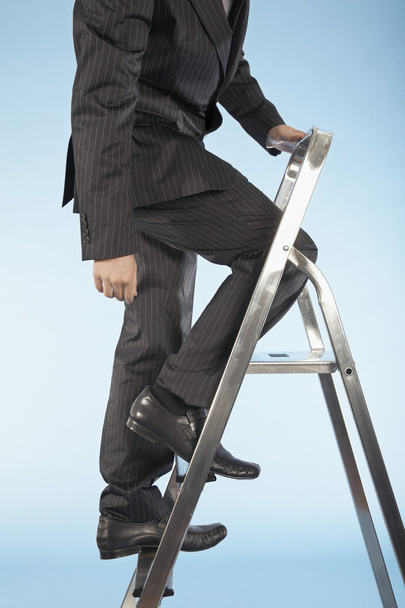 Businessman ascending ladder - Zdjęcie, obraz
