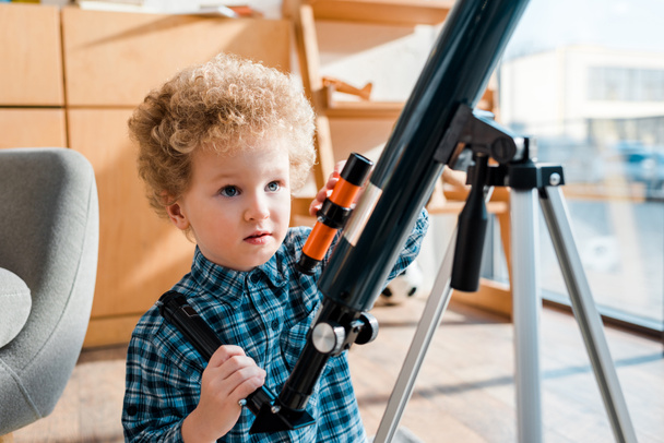 chytré a kudrnaté dítě při pohledu na dalekohled  - Fotografie, Obrázek