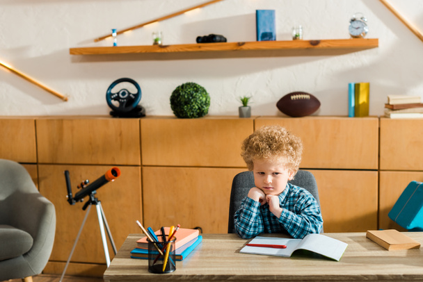 bambino sconvolto seduto alla scrivania con libri
  - Foto, immagini