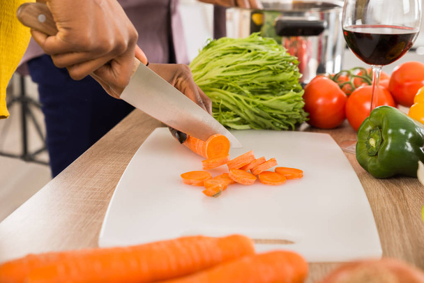 Close-up Of Woman's Hand Chopping Carrot On Cutting Board - Fotó, kép