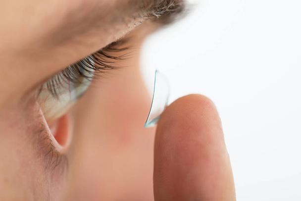 Close-up Of Young Man Putting Contact Lens In Eye - Foto, afbeelding