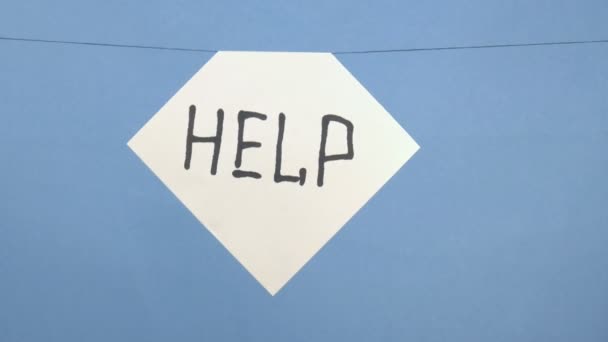 Κάψιμο και κάπνισμα λευκό φύλλο χαρτιού με μια μαύρη επιγραφή "βοήθεια" σε μπλε φόντο - Πλάνα, βίντεο