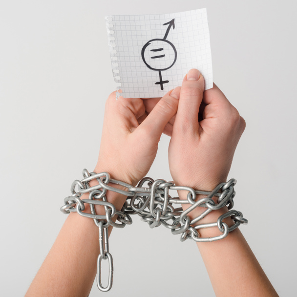 oříznutý pohled na ženu v řetězech držící papír se symbolem pohlaví izolovaným na bílém, konceptu sexuální rovnosti  - Fotografie, Obrázek