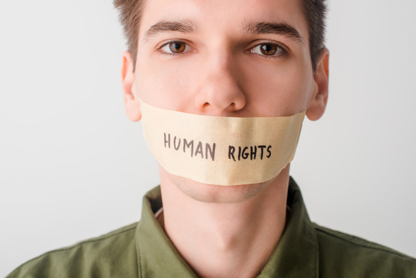 man met duct tape op mond met mensenrechtenbelettering geïsoleerd op wit - Foto, afbeelding
