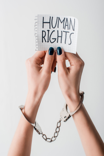 cropped view of handcuffed woman holding paper with human rights lettering isolated on white  - Фото, изображение