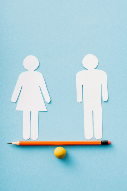 paper figures of couple as gender equality on pencil with ball isolated on blue, sexual equality concept  - Photo, Image