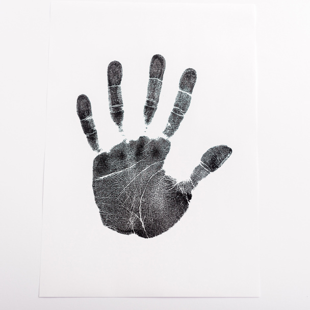 bovenaanzicht van zwarte handafdruk op papier geïsoleerd op wit, mensenrechtenconcept  - Foto, afbeelding