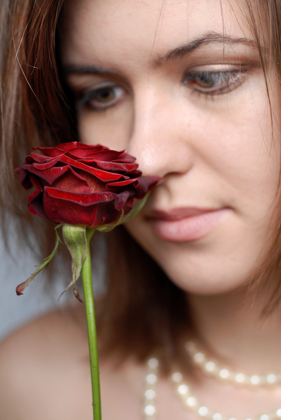 Woman looking at red rose - Φωτογραφία, εικόνα