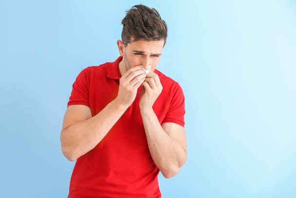Mladý muž trpící alergií na barevném pozadí - Fotografie, Obrázek
