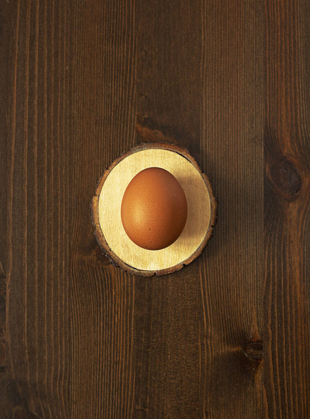 A whole raw brown egg on a light Board on a dark brown wooden background - Photo, Image