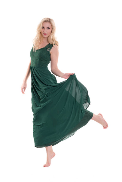 beautiful blond woman in long green evening dress is standing on tiptoes - 写真・画像