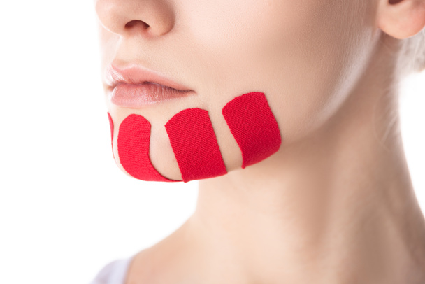 Cropped view of kinesiology tapes on chin of young woman isolated on white - Foto, imagen