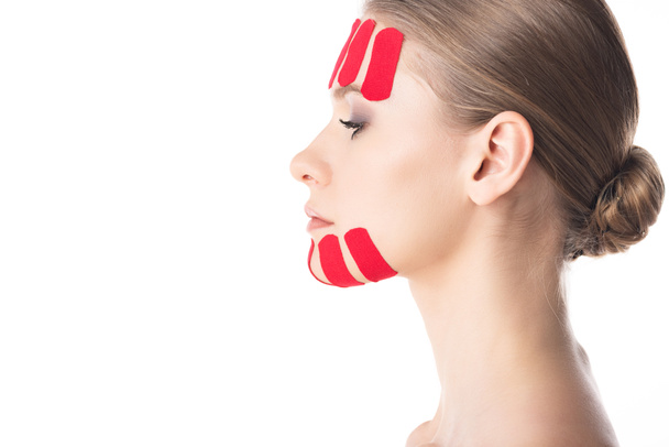 Side view of beautiful girl with kinesiology tapes on face isolated on white  - Фото, изображение