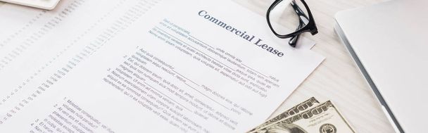 panoramic shot of documents with commercial lease lettering near money and glasses on desk  - Photo, Image