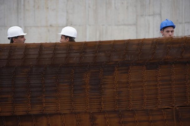 Bauarbeiter hinter einem Stapel Eisenstangen - Foto, Bild