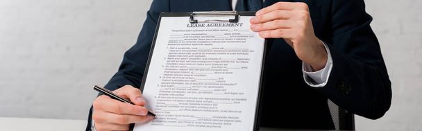 panoramic shot of realtor holding clipboard with lease agreement lettering on white - 写真・画像