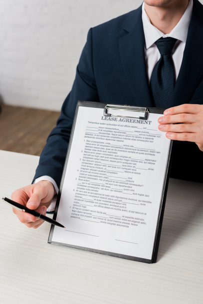 cropped view of agent holding clipboard with lease agreement lettering and pen - Fotoğraf, Görsel