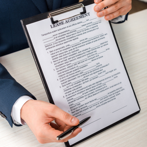 cropped view of businessman holding clipboard with lease agreement lettering and pen  - Fotoğraf, Görsel