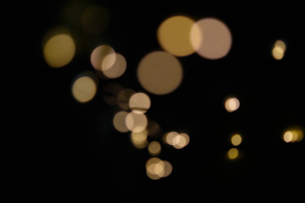 Bright defocused, golden and yellow lights on black background - Foto, afbeelding