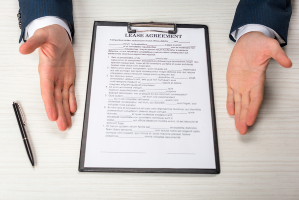 cropped view of businessman near clipboard with lease agreement lettering and pen  - 写真・画像