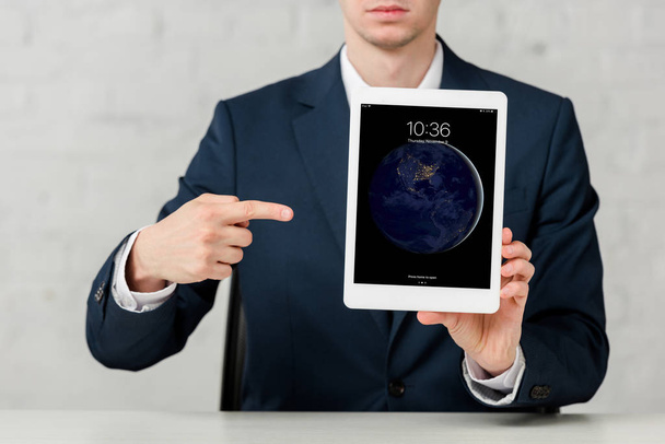 cropped view of realtor in suit pointing with finger at ipad on white  - Foto, imagen