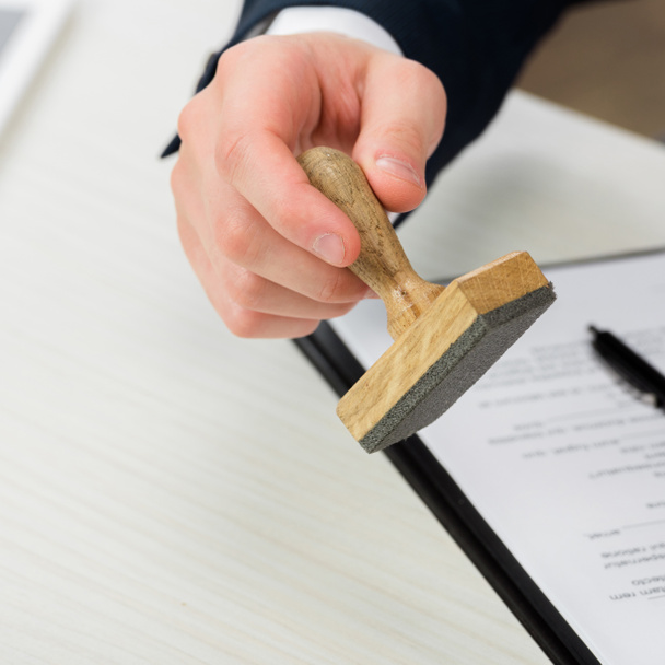 cropped view of realtor holding stamp near clipboard on desk, leasing concept  - 写真・画像