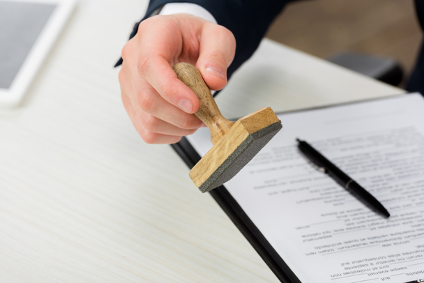 cropped view of realtor holding stamp near clipboard and pen on desk, leasing concept  - Fotoğraf, Görsel