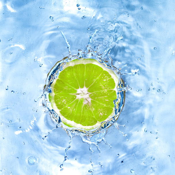 Fresh lime dropped into water with bubbles isolated on white - Fotó, kép