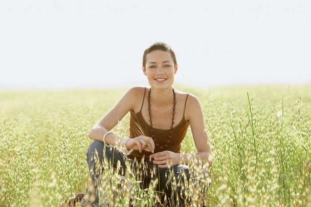 Молодая женщина, приседающая в поле
 - Фото, изображение