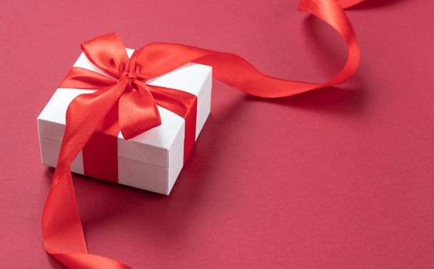Λευκό κουτί δώρου με κόκκινη κορδέλα σε λευκό φόντο.side view. Ώρα διακοπών σε οποιαδήποτε εποχή του έτους - Φωτογραφία, εικόνα