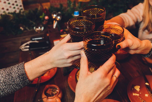 Close up shot of group of people clinking glasses with wine or champagne in front of bokeh background. older people hands. - Photo, Image