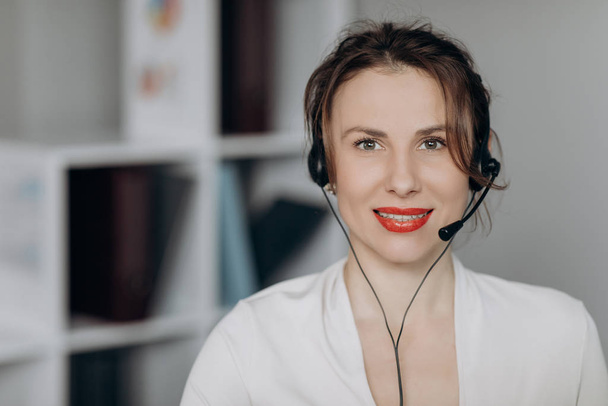 Young female customer service agent talking to a customer with a telephony headset as she looks at the camera. - Fotoğraf, Görsel