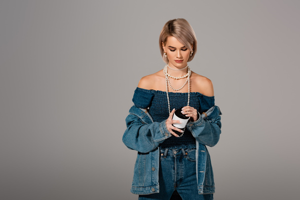 attractive woman in denim jacket holding insulated mug isolated on grey - Photo, image