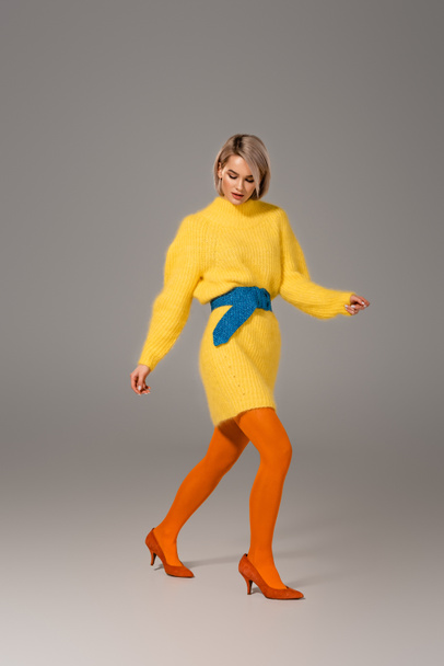 atractiva mujer en vestido amarillo caminando sobre fondo gris
  - Foto, imagen