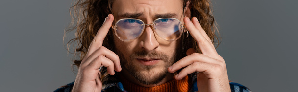 panoráma lövés jóképű férfi szemüvegben nézi kamera elszigetelt szürke - Fotó, kép