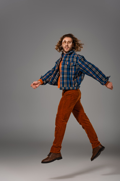 handsome man in shirt and trousers jumping on grey background  - Zdjęcie, obraz