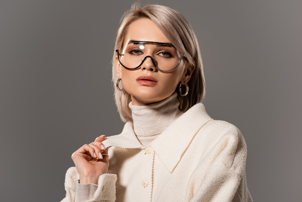 attractive woman in glasses and coat looking at camera isolated on grey - Fotoğraf, Görsel