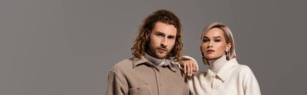 πανοραμική φωτογραφία της γυναίκας με λευκό παλτό και του άνδρα με πουκάμισο κοιτάζοντας κάμερα που απομονώνονται σε γκρι - Φωτογραφία, εικόνα