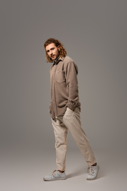 handsome man in shirt and trousers walking on grey background  - Φωτογραφία, εικόνα