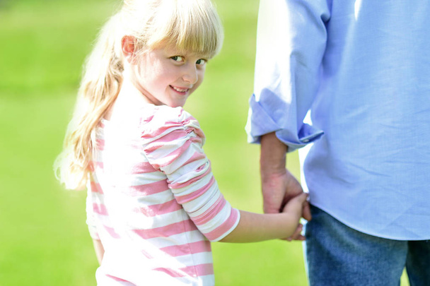 Girl holding hands with her father outside - Фото, изображение